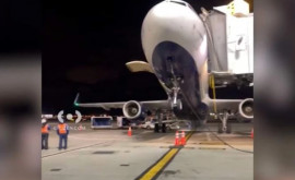 Un avion se ridică pe coadă în timp ce este descărcat de bagaje