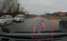 Momentul în care o fetiță sare în fața unei mașini și traversează strada